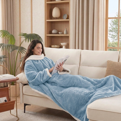 Woman reading on a sofa wearing the Kokoon light blue wearable heated blanket in a Japandi-style living room